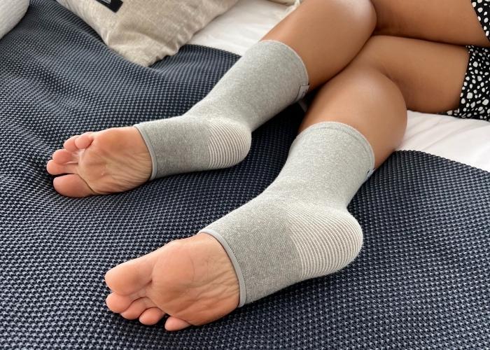 Person wearing a compression knee sleeve for joint support and pain relief while outdoors.